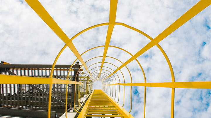 Looking up inside a metal yellow ladder in protective scaffolding